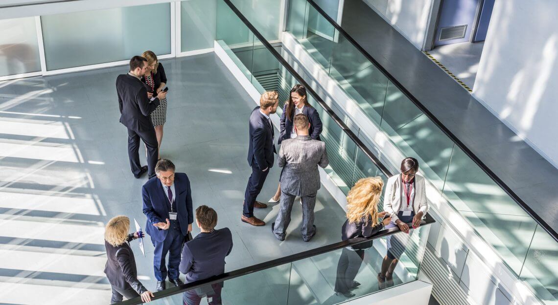 An aerial view of a sunny, modern office with professionals networking.