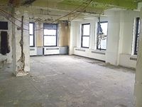 Open plan space with large windows, and exposed ceilings