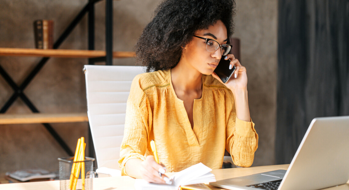 An african-american young woman making a phone call in a modern NYC office