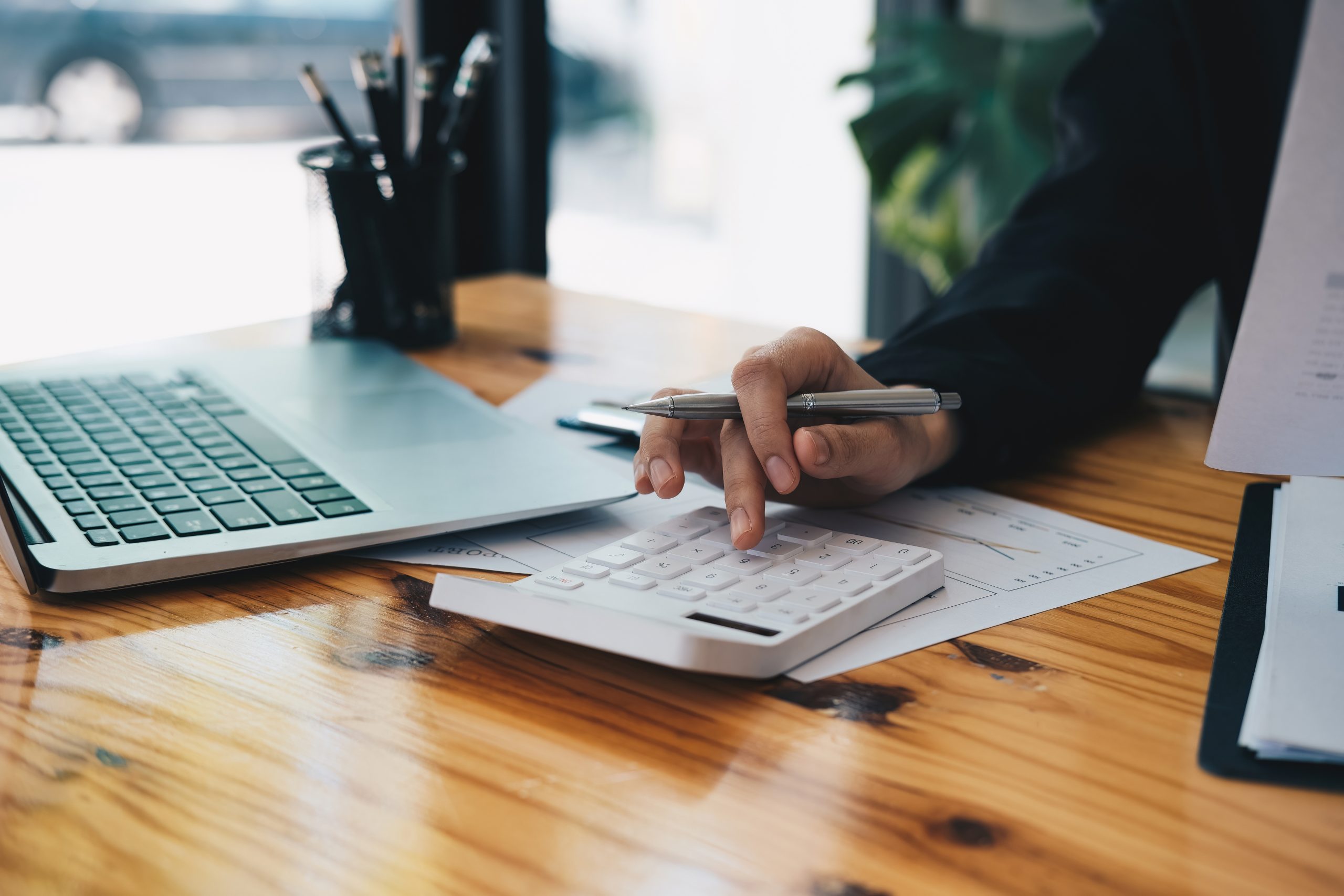 A person using a calculator at a desk with financial documents.