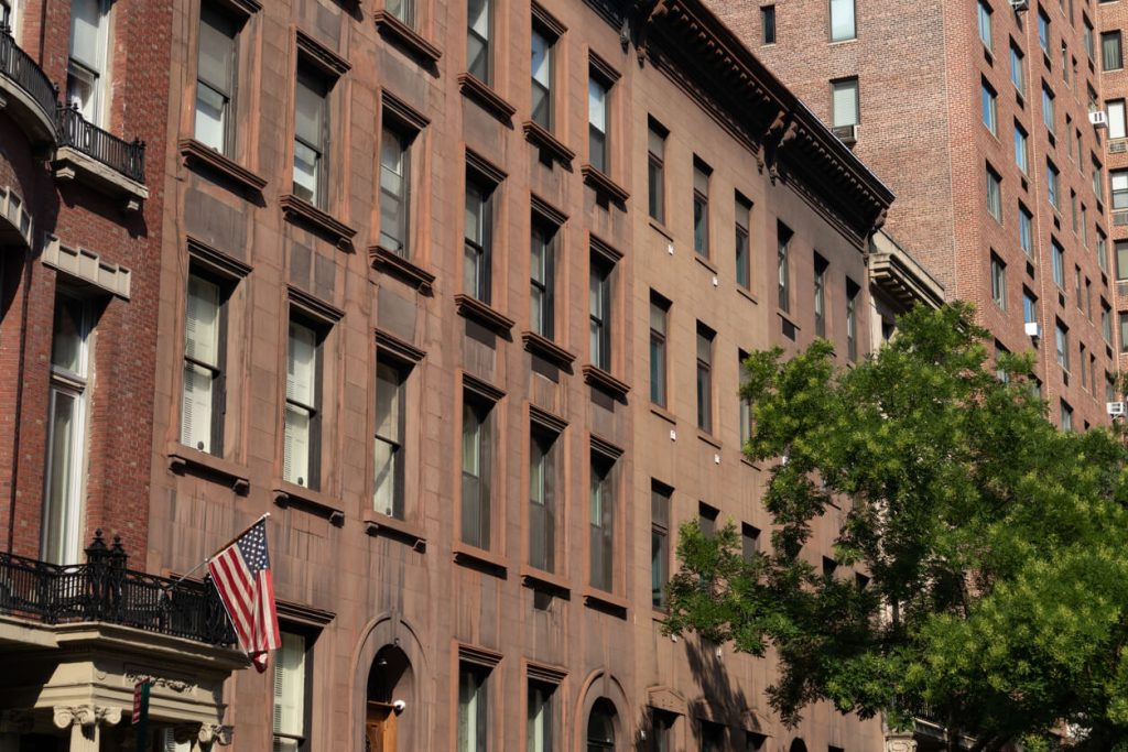 Old stone & brick buildings in Murray Hill, NYC with a hanging American flag