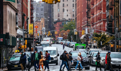 Pedestrians dash across bustling Lafayette Street, taxis and idling cars at a busy intersection
