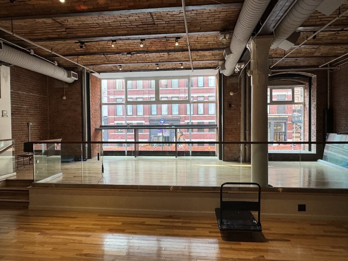 Empty loft with wooden floors, exposed brick, and industrial ductwork.