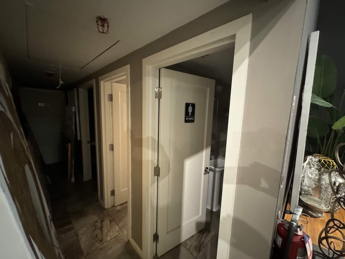 Dim hallway at 44 West 24th St with doors, restroom sign, fire extinguisher.