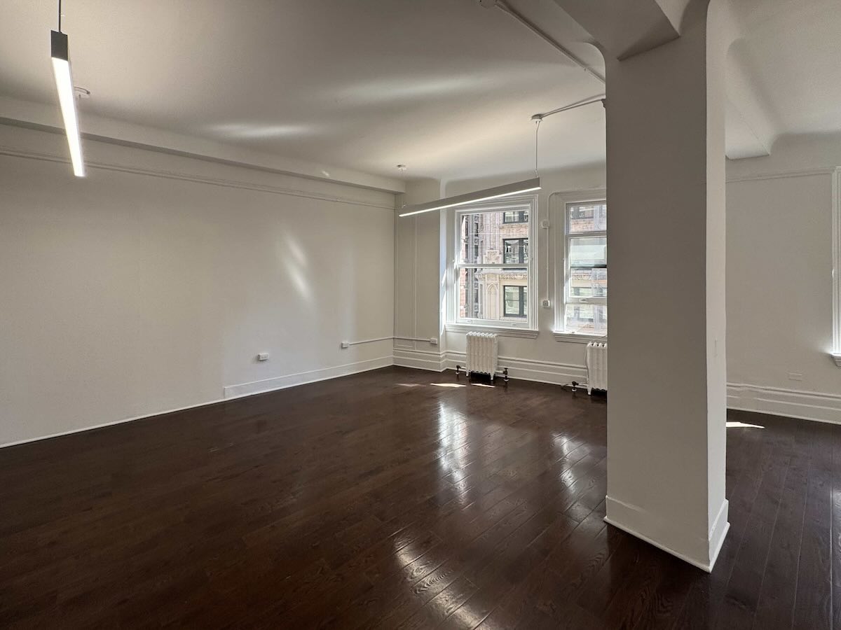 Spacious room with dark floors, white walls, and large windows at1133 Broadway, #630