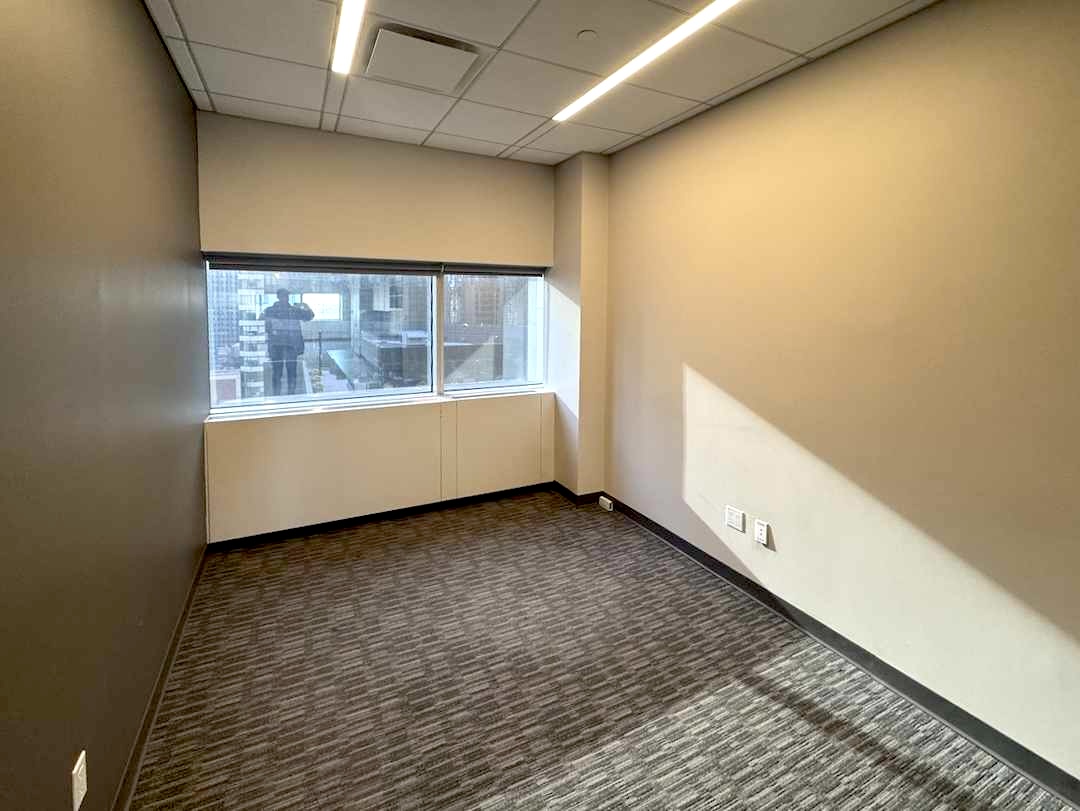 Empty office on 20th floor, gray walls, carpet, window.