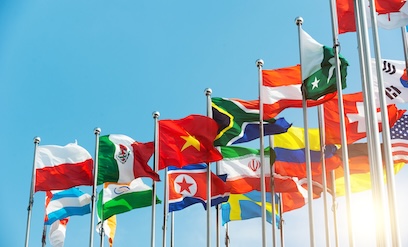 International flags waving in a bright blue sky, sun shining.