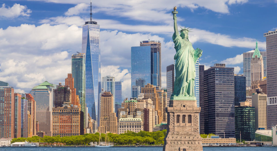 Statue of Liberty with NYC skyline and One World Trade Center behind.