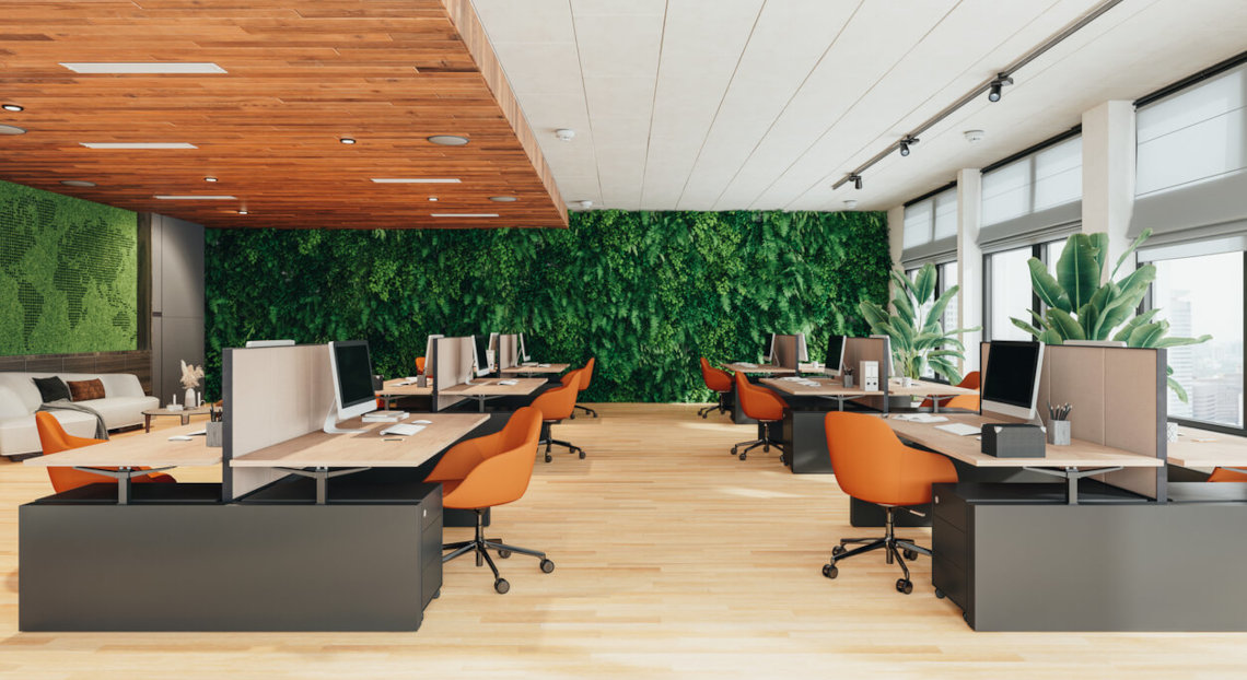 Modern office with orange chairs, green plant wall, and large windows.