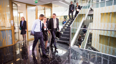 Business professionals walk and talk in a modern office building.