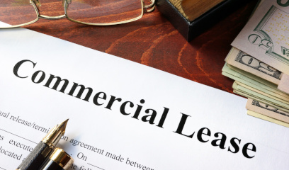 Commercial Lease document on desk with pen, eyeglasses, and cash nearby.